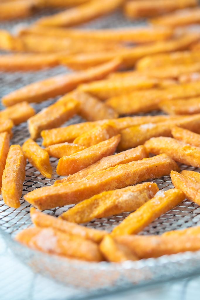A close up of frozen sweet potato fries on an air fryer tray.