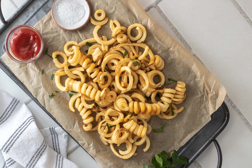 Top down shot of air fried curly fries on a table.