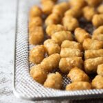 A close up of a bowl of air fried tater tots.