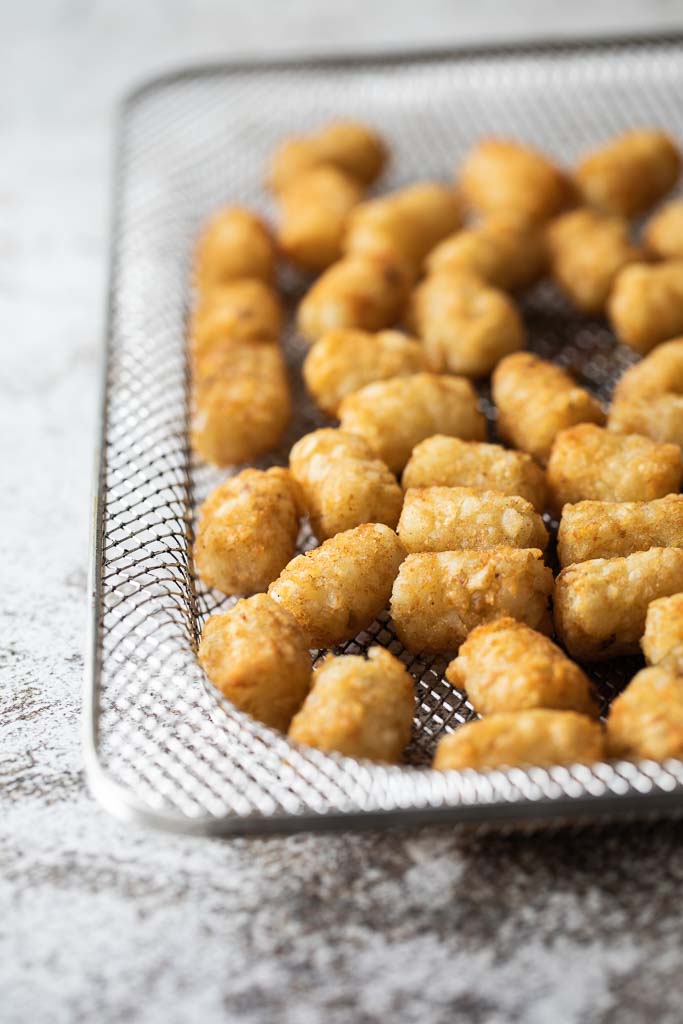 A close up of a bowl of air fried tater tots.