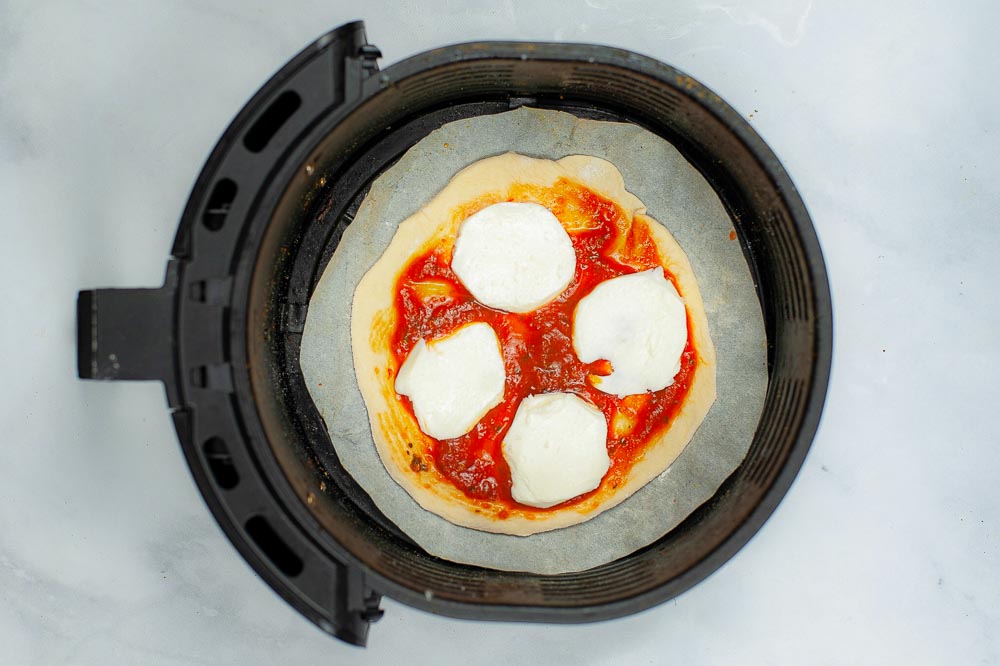 A homemade air fryer pizza shown before cooking in an air fryer.