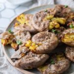 Smashed potatoes stacked on a plate.