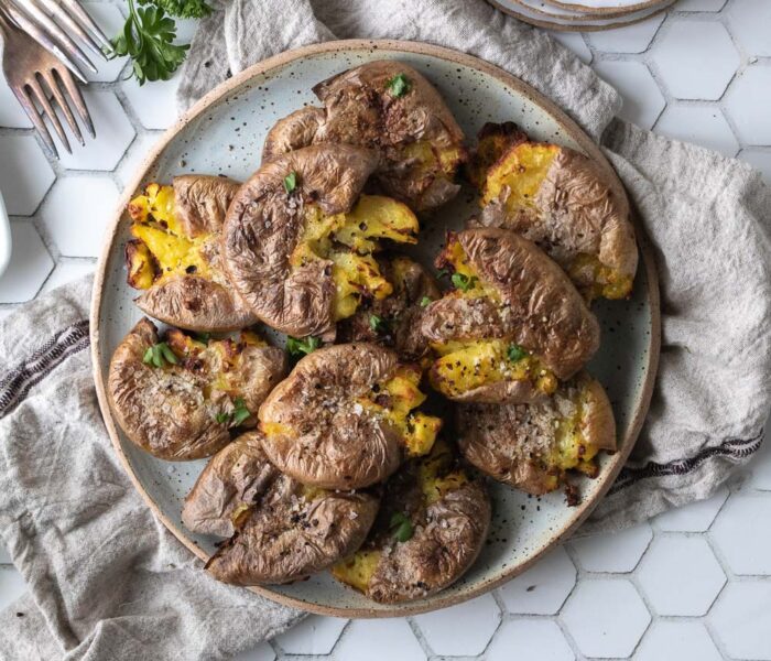 Top down view of smashed potatoes on a plate.