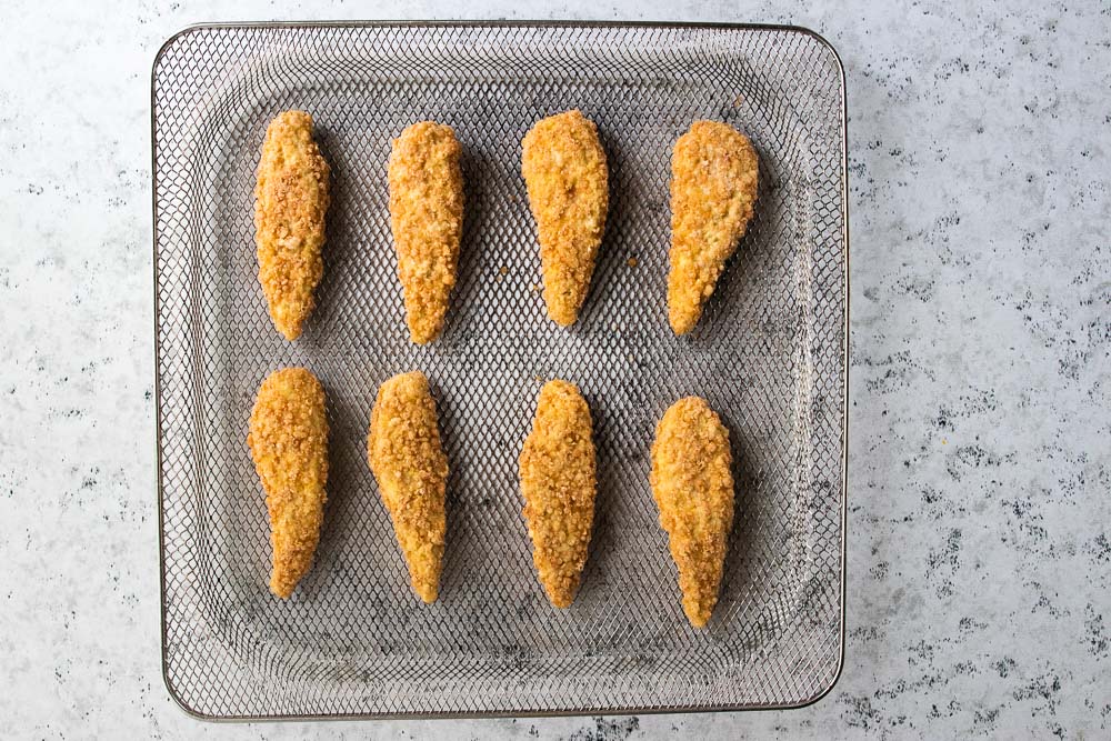 air fryer tray covered in 8 chicken tenders