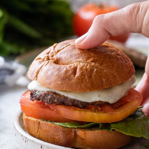 a person's hand taking a burger that's on a bun