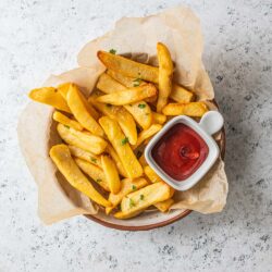 a bowl of steak fries cooked with a small bowl of ketchup