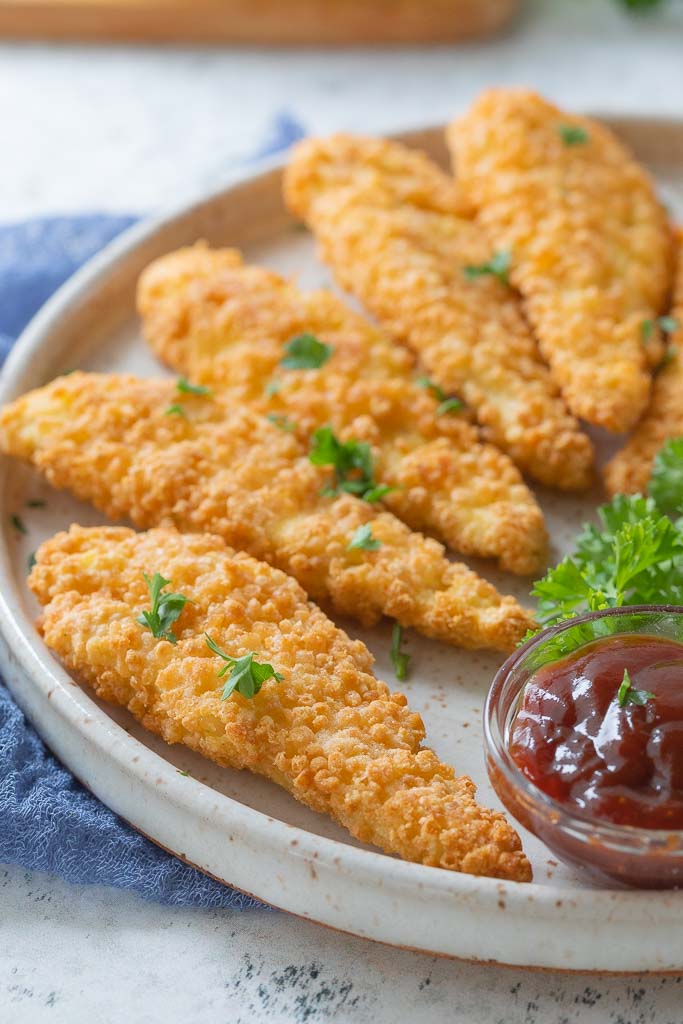 cooked chicken tenders on a plate with sauce