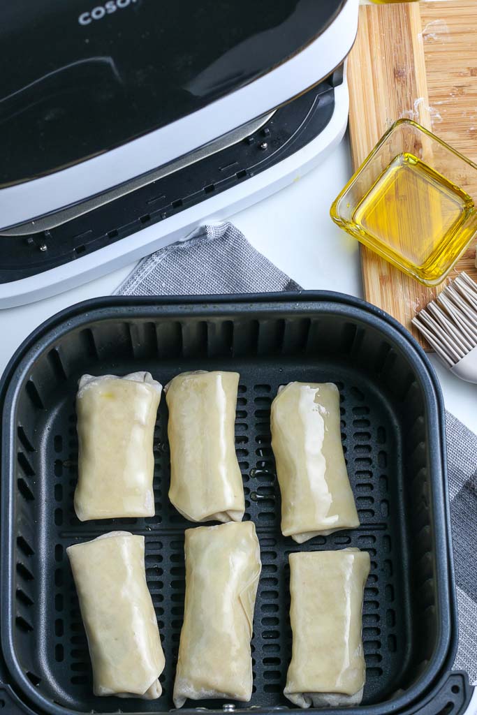 six southwest eggs rolls, ready to be cooked in an air fryer basket