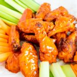 Chicken wings cooked and covered in buffalo sauce served with raw veggies.