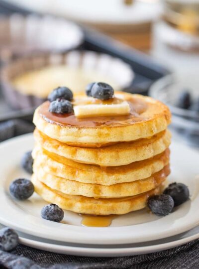 Pancakes topped with syrup, butter, and blueberries.
