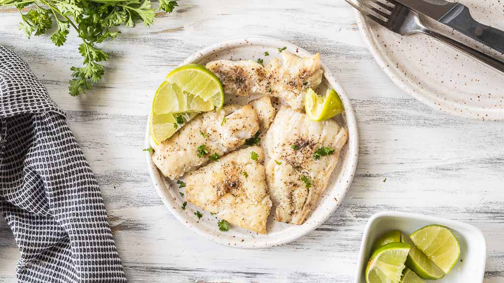 Overhead view of cooked tilapia on a serving plate.