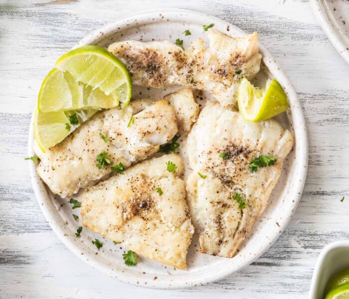 Tilapia on a serving plate garnished with lime.