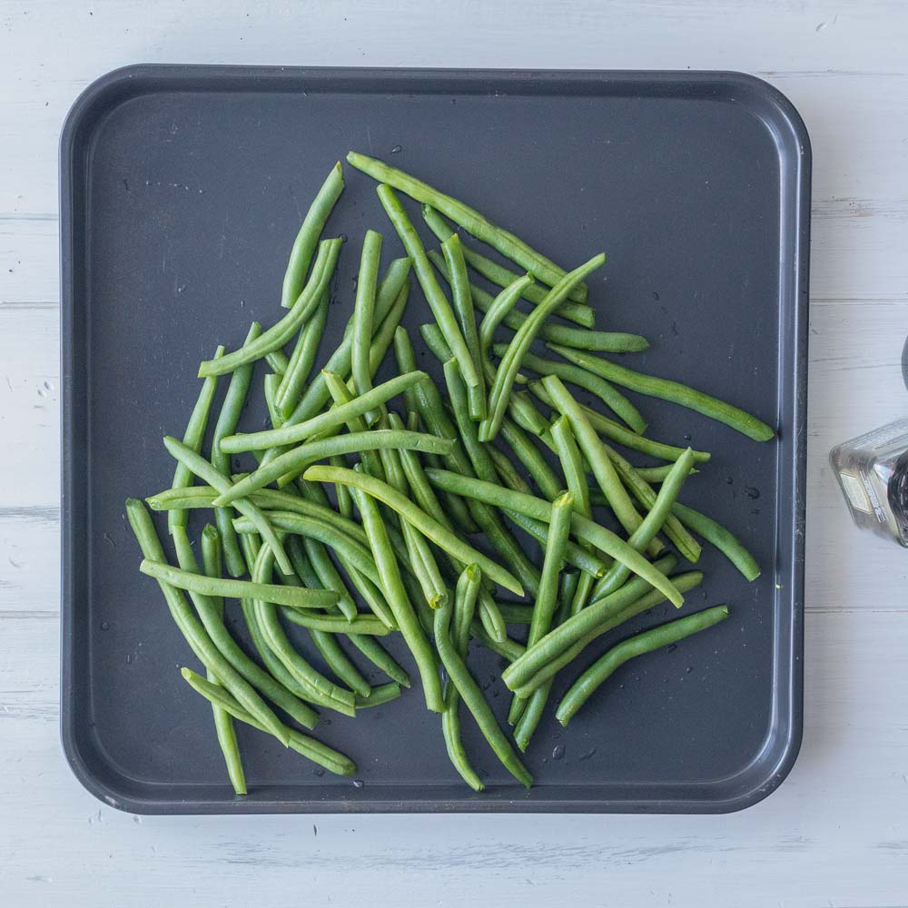 Green beans on an air fryer baking sheet.